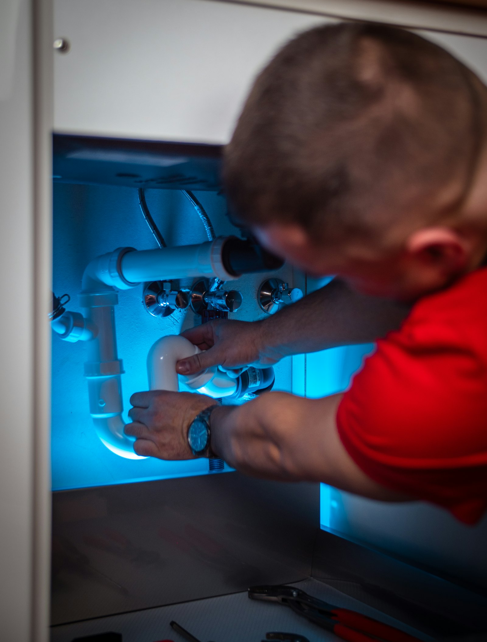 Plumber repairing pipes under a kitchen sink